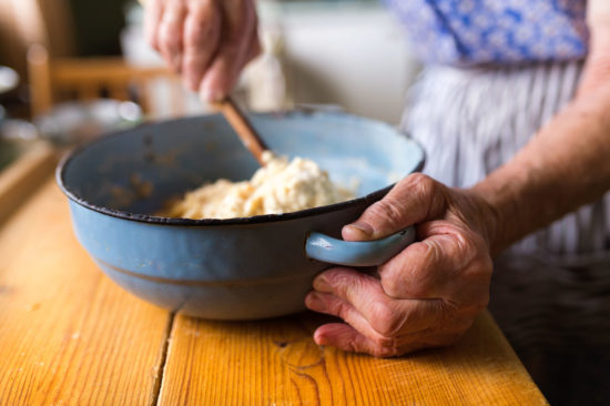 senior woman baking pies in her home kitchen. mixing ingredients.